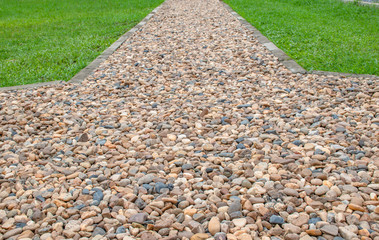 Walkway paved with gravel beside a green lawn.