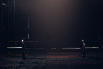 Bar for weight lifting on dark background in gym barbell.