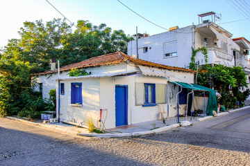 Fototapeta na wymiar Facade of a very small white house with blue windows in Halkidiki, Greece
