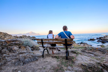 Halkidiki, Greece. Married couple sit at bench watching sea and think positively - Powered by Adobe