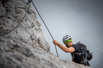 Male climber on a via ferrata - climbing on a rock in Swiss Alps