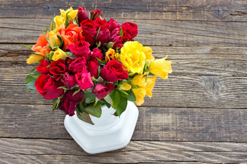 Roses in ceramic vase on wooden background