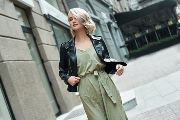 Obraz premium Fashion. Young stylish woman walking on the city street looking aside smiling curious