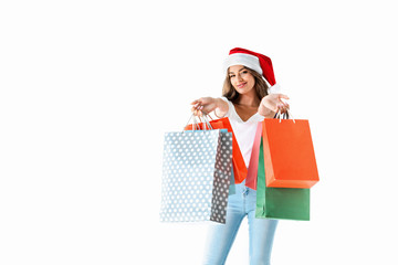 attractive smiling girl in santa hat holding shopping bags, isolated on white