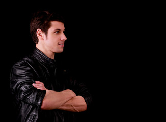 Muscular handsome young man smiling with black tee shirt in front of black background
