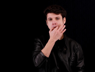 Muscular handsome young man whistling with black jacket in front of black background