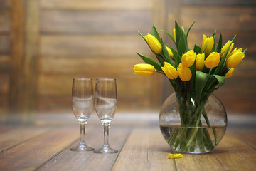 A bouquet of yellow tulips in a vase on the floor. A gift to a w