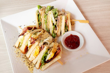 Club sandwich on a white plate on a wooden table