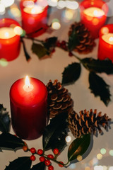 Christmas and New Year composition. Lit candles, fir cones and branch of holly