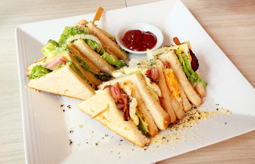 Club sandwich on a white plate on a wooden table