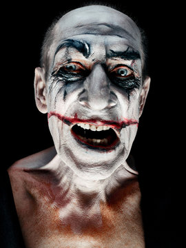 Bloody Halloween theme: The crazy smiling maniak face on dark studio background