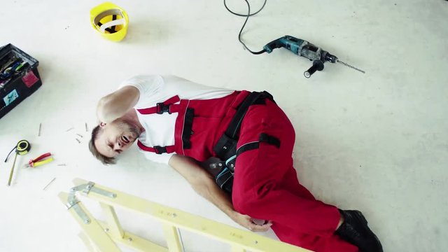 Top view of an injured man lying on the floor after an accident at work.