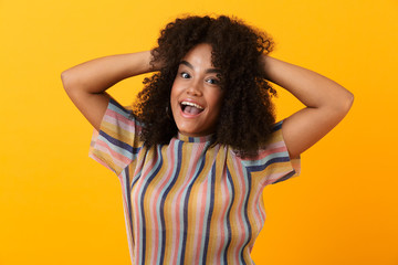 Emotional excited pretty african woman isolated over yellow background.