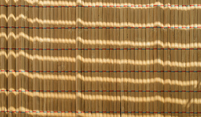 Sushi roll bamboo mat with sunlight spots.