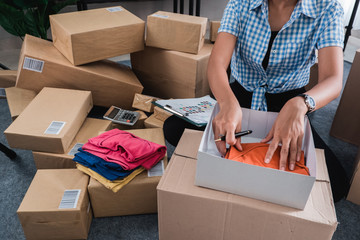 Young woman packing of clothes put on the boxes