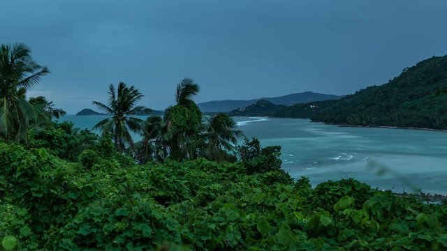 Tropical palm trees stagger from the wind against the background of the sea and mountains of Koh Samui, Thailand. Timelapse 4K