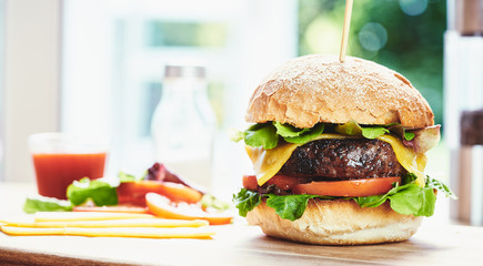 A cheese burger in a crusty bun with lettuce and tomatoes on a c