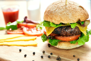 A cheese burger in a crusty bun with lettuce and tomatoes on a c