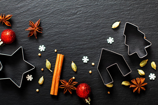 Holiday Food background Christmas cookies cutter spices Star anise, cloves and cadamon pods on black slate board