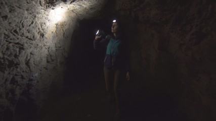 Fototapeta na wymiar portrait of a girl, the tourist, the researcher goes into the cave with a flashlight
