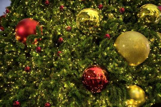 Close up background image of decorated outdoor Christmas tree with colorful lights and ornaments