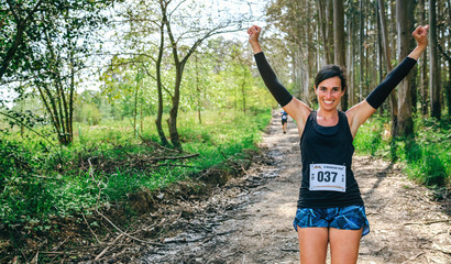 Young woman winning a trail race in the forest