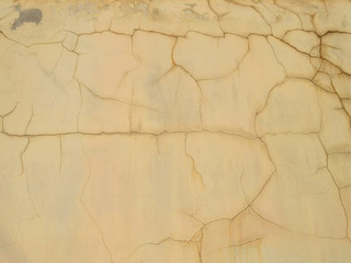 Plastered and painted yellow wall, covered with numerous cracks, texture for background