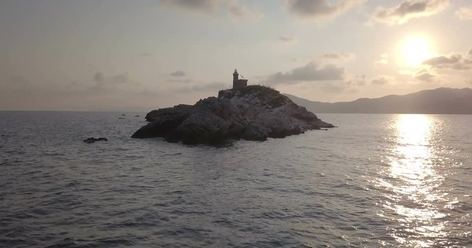Aerial view at dawn of a lighthouse on the summit of a rocky islet without vegetation in front of Portoferraio, Elba island (Italy)
