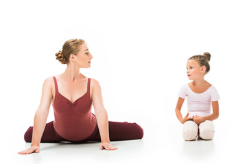 Obraz na płótnie Canvas smiling adult female coach showing exercise to little ballerina isolated on white background