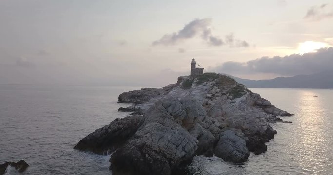 Aerial view at dawn of a lighthouse on the summit of a rocky islet without vegetation in front of Portoferraio, Elba island (Italy)