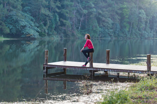 woman sitting on the wooden bridge of the lake