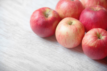 Red apples on a light wooden background