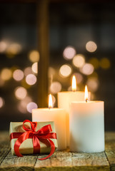 Obraz na płótnie Canvas Three white christmas candles with sparkling light background