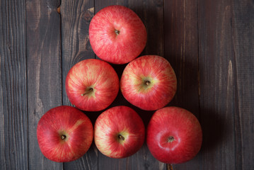 Triangle of red apples on a brown wooden background