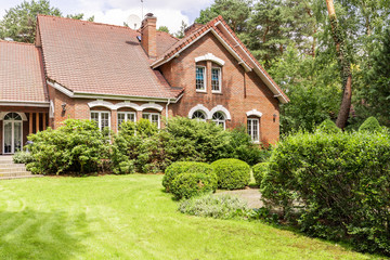 Real photo of garden with bushes and beautiful brick house