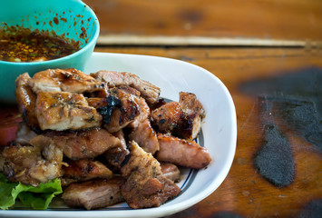 Sliced pork roasted thai style with green leaves salad on rustic plate with cutlery. charcoalboiled pork neck Grill pork Thai style food