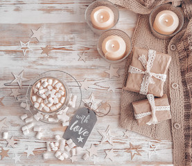 Fototapeta na wymiar cozy winter composition with Christmas greeting card, coffee, marshmallow, knitted sweater and candles. Christmas holiday concept, delicious food, decor. copy space