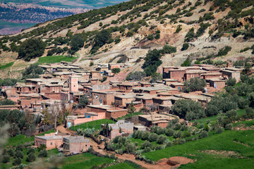 Fototapeta na wymiar A small settlement in the Atlas Mountains. The mountain range is covered with bright green vegetation. Africa Morocco