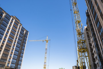 Construction of a high-rise building with a crane. Building construction using formwork. Cranes and buildings against the blue sky.