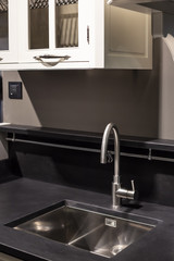 Black and white kitchen interior with dark countertop, and chrome water tap