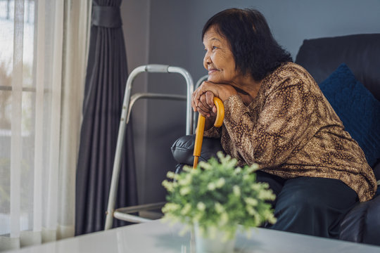 happy senior woman with wooden cane in living room
