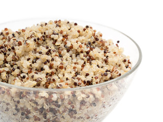 Fototapeta na wymiar Close up of cooked mixed quinoa seeds in a round glass bowl seen from the side and isolated on white background