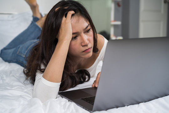 stressed woman using laptop computer on bed