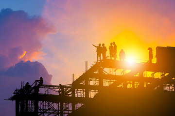 Fototapeta premium Silhouette of Engineer and worker on building site, construction site with clipping path at sunset in evening time.