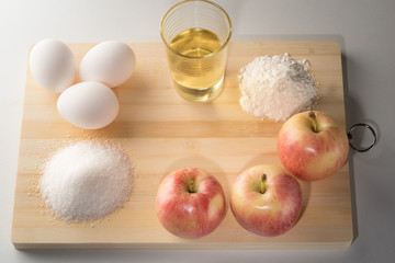 Ingredients for baking apple pie or cake.Preparing for a Christmas cake with apples.Copy space. Apple, flour, eggs, sugar, cranberries on a wooden board in daylight in the kitchen.