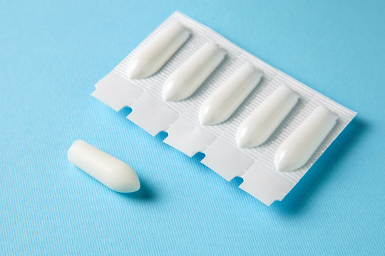 Suppository for anal or vaginal use on a blue background. Candles for treatment of hemorrhoids, temperature, thrush, inflammation