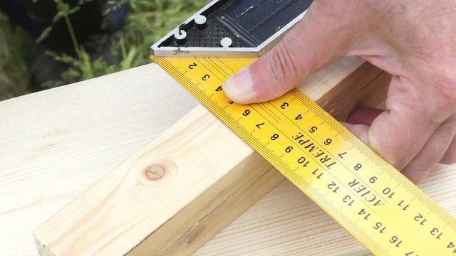 Man measures the angle of 90 degrees with the help of a construction corner