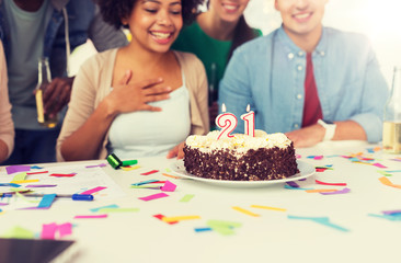 corporate, celebration and people concept - happy team with cake at office party greeting coworker with twenty first birthday