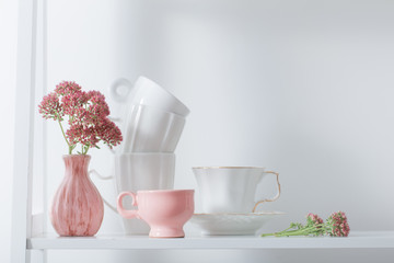 Clean dishes and flowers on wooden shelf
