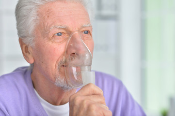 Portrait of senior man with inhaler at home